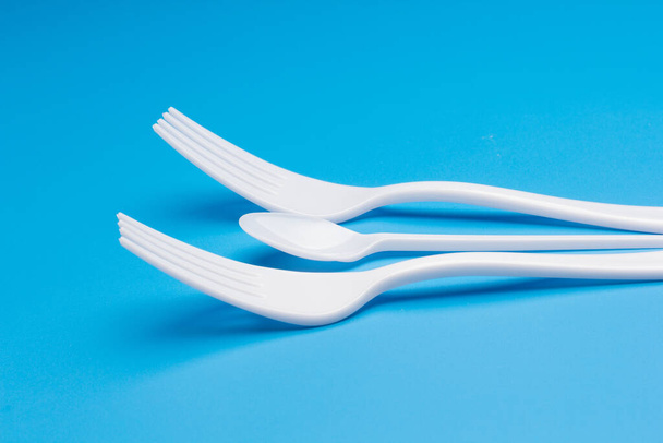 Cutlery for eating white and made of plastic and transparent glass cups; Cutlery and glasses teaspoons for coffee and for rationing small amounts of sugar, fork for pricking food, glasses for drinking - Foto, afbeelding