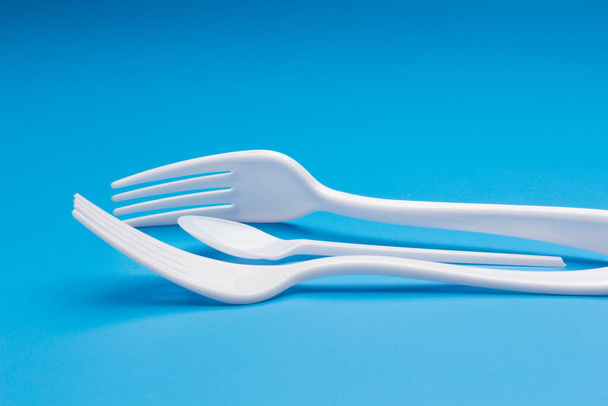 Cutlery for eating white and made of plastic and transparent glass cups; Cutlery and glasses teaspoons for coffee and for rationing small amounts of sugar, fork for pricking food, glasses for drinking - Φωτογραφία, εικόνα