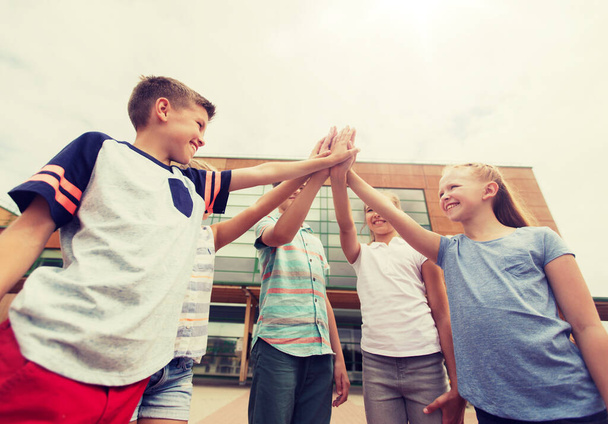 grupo de crianças fazendo alta cinco no pátio da escola
 - Foto, Imagem