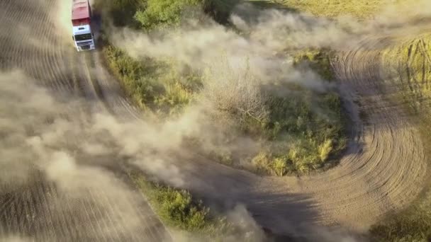 Letecký pohled na náklaďák jedoucí po prašné cestě mezi oranými poli a vytvářející spoustu prachu. - Záběry, video