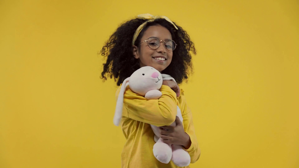 happy african american kid taking soft toy isolated on yellow  - Materiał filmowy, wideo