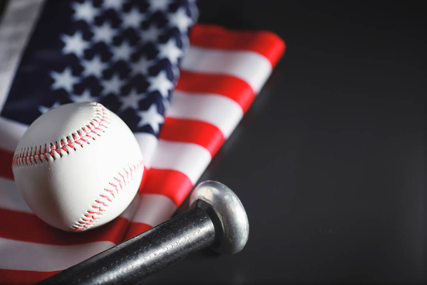 Amerykańska tradycyjna gra sportowa. Baseball. Koncepcja. Baseball i nietoperze na stole z amerykańską flagą. - Zdjęcie, obraz