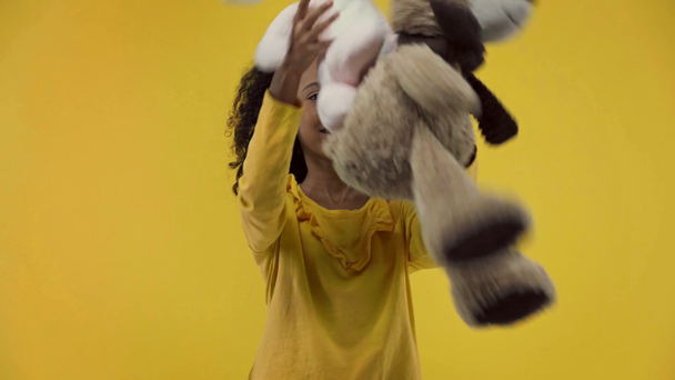 cheerful african american kid with soft toys isolated on yellow  - Záběry, video