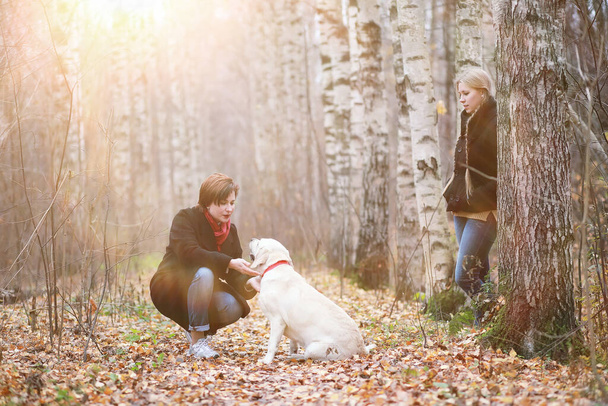 Teen girl with mother on dog walk in the autumn garden - Photo, Image