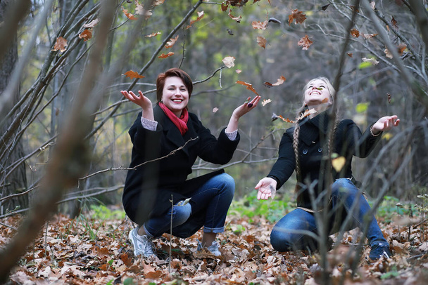 Pretty woman with teen daughter on a walk in the autumn garden - Photo, Image