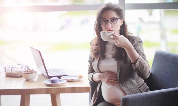 Terhes nő dolgozik ebéd közben számítógépen kávézóban - Fotó, kép