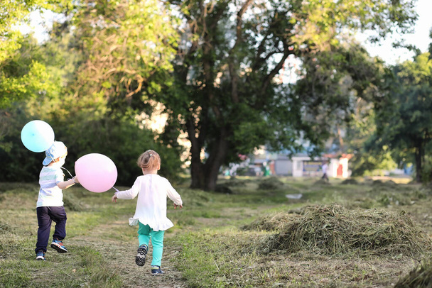 Little children are walking in a park with balloons - Photo, image