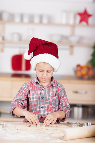 Cute little boy in the kitchen in a red Santa Hat - Фото, зображення