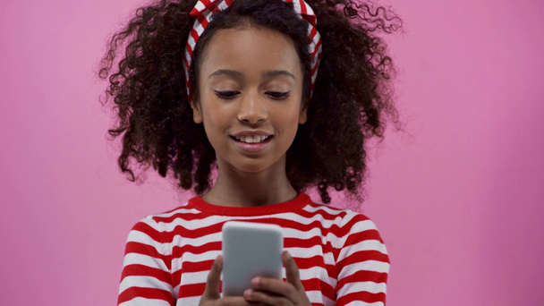 Focus pull de niño afroamericano con smartphone aislado en rosa
  - Metraje, vídeo