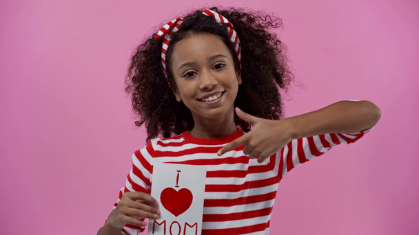 niño afroamericano con tarjeta de felicitación en el día de las madres aislado en rosa
  - Imágenes, Vídeo