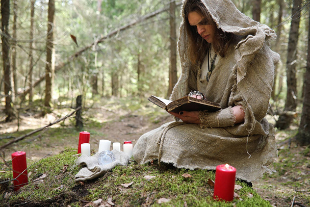 ein Mann in Soutane verbringt ein Ritual in einem dunklen Wald mit Kristallkugel und Buh - Foto, Bild