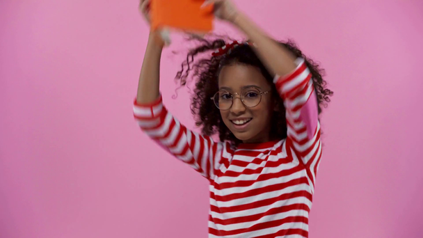 кучеряве афроамериканське дитя з книгою на голові ізольовано на рожевому
  - Кадри, відео