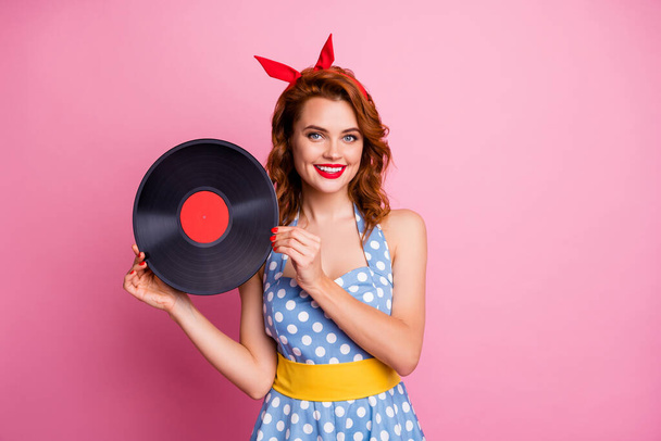 Photo of elegant lady hold old fashion vinyl cd record bring collection single to retro theme party event wear dotted dress red headband yellow belt isolated pink color background - Fotó, kép