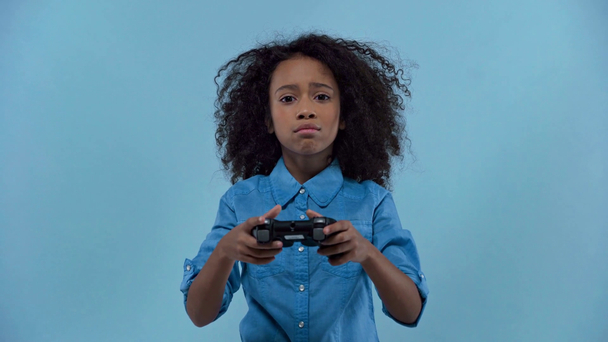 KYIV, UKRAINE - JANUARY 20, 2020: african american kid playing video game isolated on blue - Video, Çekim