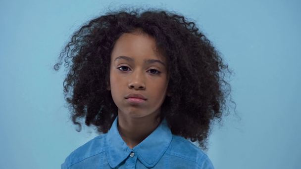 χαριτωμένο αφροαμερικανό παιδί κοιτάζοντας κάμερα απομονωμένη στο μπλε  - Πλάνα, βίντεο