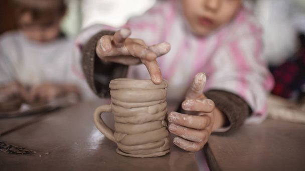 Cute małe dzieci bawiące się razem z modelingu gliny w warsztacie garncarskim, rzemiosła i sztuki gliny, działalności twórczej dzieci, edukacji w sztuce - Zdjęcie, obraz