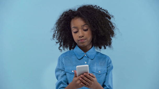 Afrikaans amerikaans kind met behulp van smartphone geïsoleerd op blauw  - Video