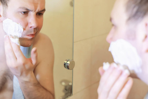 Een man scheert zich in de badkamer in de ochtend voor het werk - Foto, afbeelding