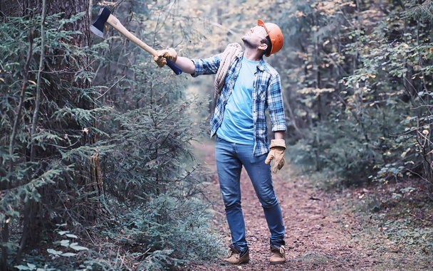 Αρσενικός ξυλοκόπος στο δάσος. Επαγγελματίας ξυλοκόπος επιθεωρεί τα δέντρα για κοπή. - Φωτογραφία, εικόνα