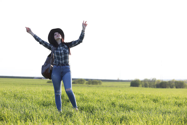 Egy lány farmerban és kalapban utazgat a nyáron vidéken. - Fotó, kép