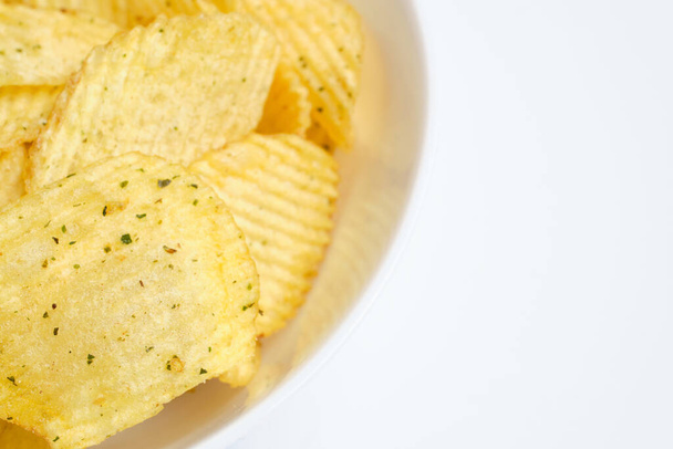 Fluted chips with spices in a white plate on a white background. Close up. - 写真・画像