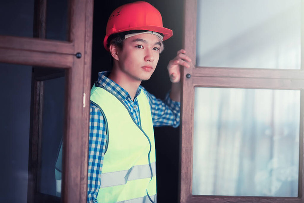 junger asiatischer Mann mit Schutzhelm und Bauweste - Foto, Bild