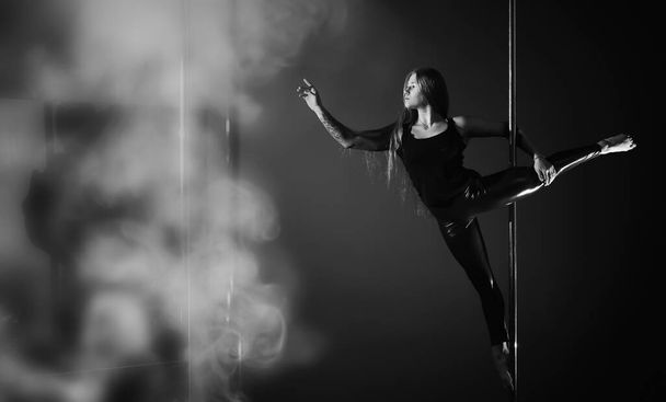 Κορίτσι που κάνει ασκήσεις σε αθλητικό εξοπλισμό. Η χορεύτρια στον πυλώνα στο στούντιο.. - Φωτογραφία, εικόνα