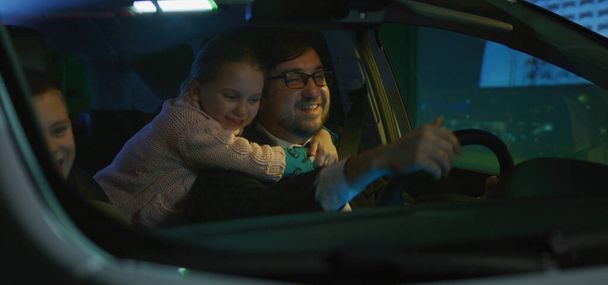 Pai dirigindo seus filhos para casa à noite
 - Foto, Imagem