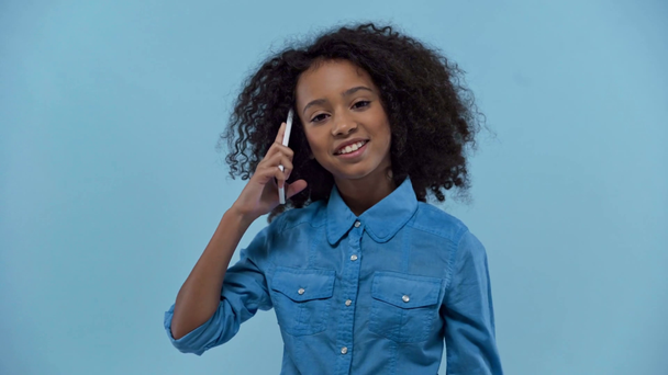 smiling african american kid talking on smartphone isolated on blue  - Felvétel, videó