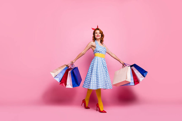 Full size photo cheerful tender elegant cute pretty girl summer weekend go shopping hold many bags enjoy purchase wear blue headband yellow tights red stilettos isolated pink color background - Photo, Image