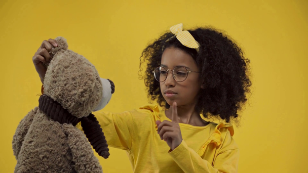 Afrikalı Amerikalı çocuk sarıda izole edilmiş yumuşak oyuncaklara jest yapmıyor. - Video, Çekim