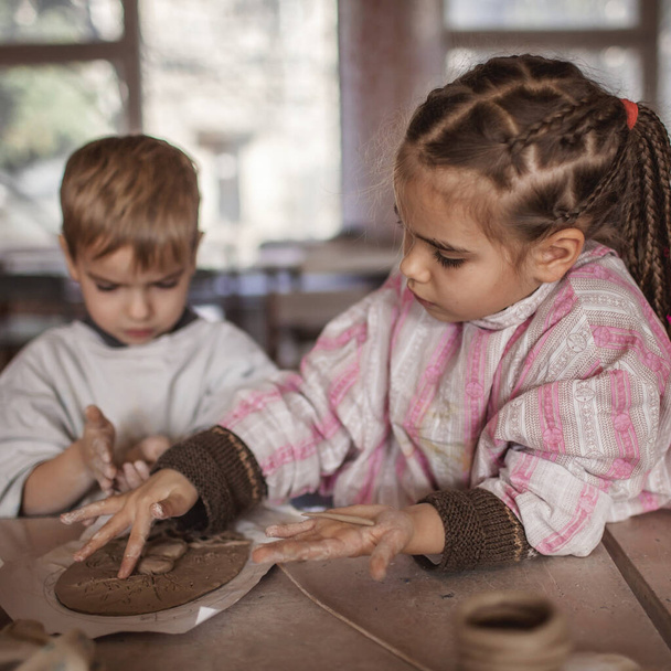 陶器のワークショップ、工芸品や粘土芸術、子供の創造的な活動、芸術の教育で粘土のモデリングと一緒に遊んでかわいい子供たち - 写真・画像