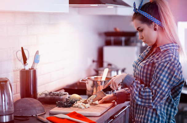 A cute young girl in the kitchen prepares dinne - Foto, afbeelding