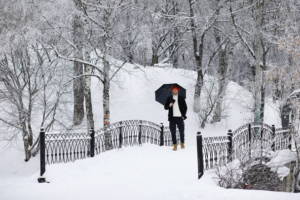 Zimní procházka s deštníkem.Muž v kabátě s deštníkem, procházka na pozadí zimní krajiny, zimní pohled - Fotografie, Obrázek