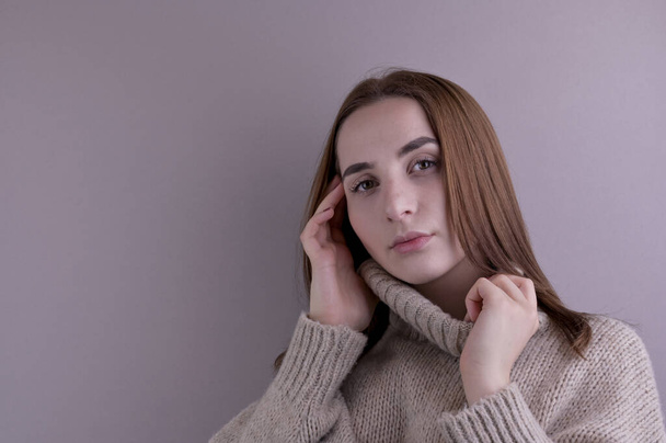Beautiful Girl in a sweater on a gray background. Studio shot. Modern portrait. Copy space. - Фото, изображение