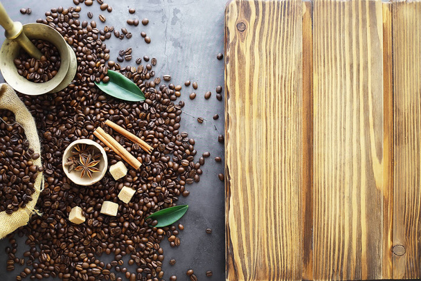 コーヒーの袋だ。テーブルの上で焙煎されたコーヒー豆。料理用の葉を持つコーヒー豆. - 写真・画像