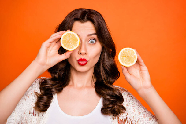 Close up photo of trendy cheerful positive nice charming pretty girlfriend hiding her eye behind lemon kissing you isolated over vibrant color background - Fotografie, Obrázek