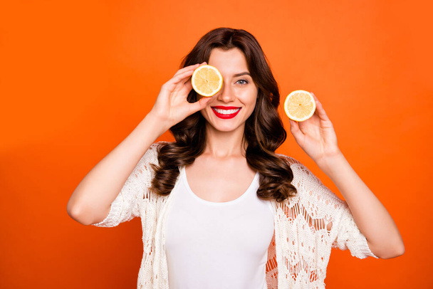 Photo of brown haired cheerful positive cute nice charming pretty girlfriend smiling toothily playfully hiding her eye behind half of lemon isolated over vivid color background - Fotografie, Obrázek