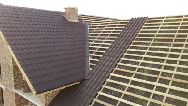 Vista aérea de casa inacabada con estructura de techo de madera cubierta con láminas de azulejos metálicos en construcción. - Imágenes, Vídeo
