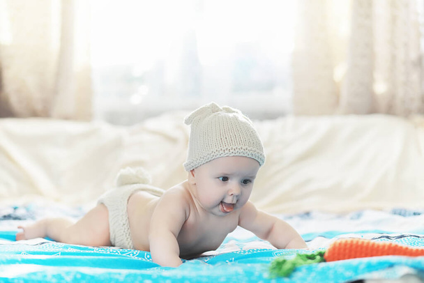 Een pasgeboren baby ligt op een zacht bed. Emoties van kinderen. - Foto, afbeelding