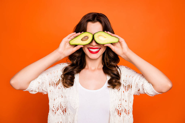 Photo of cheerful positive nice charming pretty wavy girlfriend hiding her eyes behind two halves of avocado isolated over vivid color background - Φωτογραφία, εικόνα