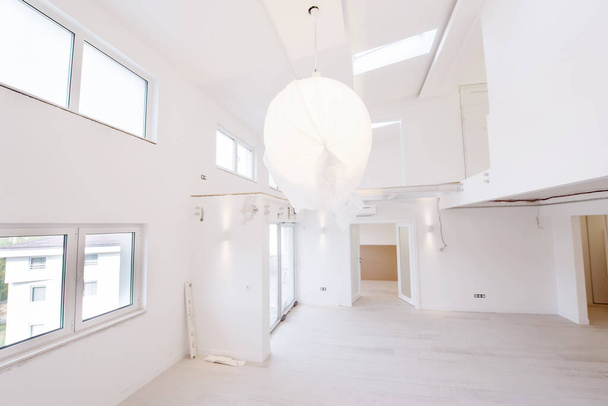 Interior of empty stylish modern open space two level apartment with white walls and large round chandelier in the middle ready to move in - Fotó, kép