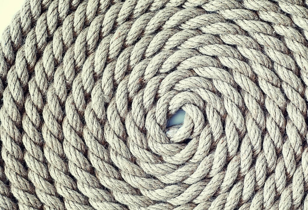 Плетемо товсту мотузку, прив'язану до перекосу. Конопляна мотузка для прикраси та дизайну. Фон з рибальської мотузки
. - Фото, зображення