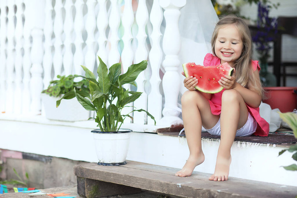 Kid eating watermelon. Summer house in the village by the garden. - Photo, Image