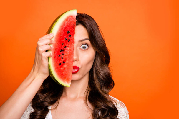 Photo of brunette haired casual close up cheerful positive flirty lady hiding half of her face behind wedge of watermelon kissing you isolated over vivid color background - Fotó, kép