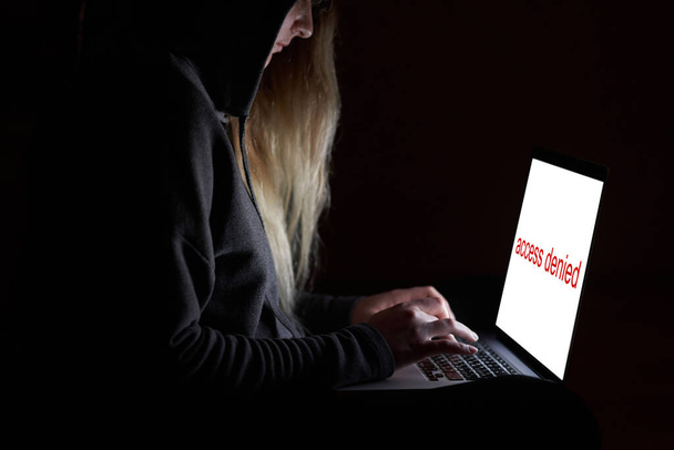 Hacker aéreo no capô trabalhando com laptop digitando texto na sala escura
.  - Foto, Imagem