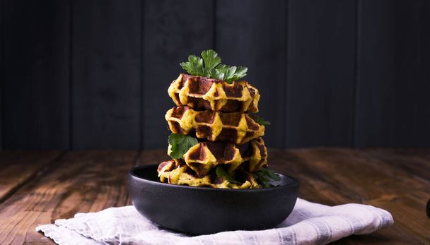 Lush belgian waffles with vegetables and herbs on a wooden table. The concept of a healthy diet and vegetarianism. Dark photo in rustic style. Free space for text. - Foto, immagini