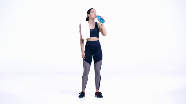 spocony sportowiec pijący wodę na białym - Materiał filmowy, wideo