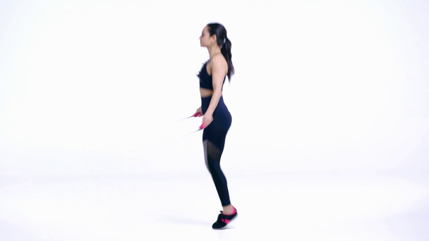 Seitenansicht einer Sportlerin, die mit Springseil auf weiß trainiert   - Filmmaterial, Video