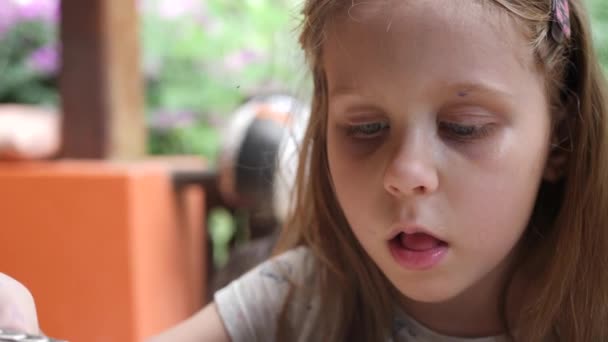 Маленька гарненька дівчинка їсть суп у саду - Кадри, відео